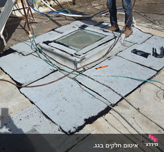 עבודת איטום על גג עם יריעות ביטומניות ואדם בעבודה